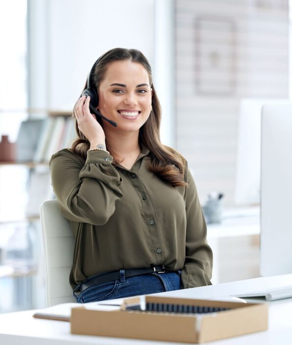 Porträt einer Frau, die ein Headset und einen Computer in einem modernen Büro benutzt.