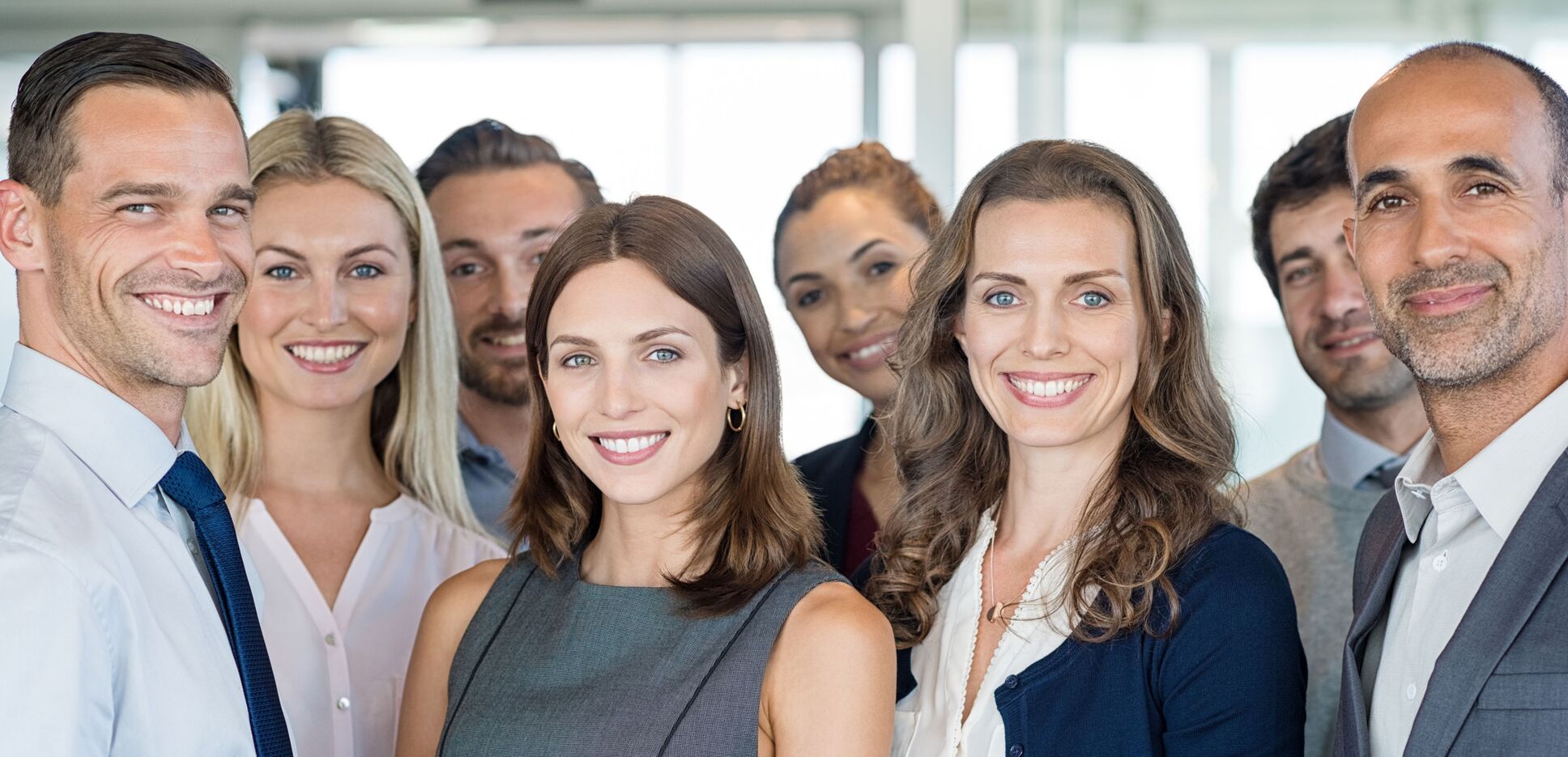 Glückliche Geschäftsleute und zufriedene Geschäftsfrauen stehen als Team im Büro