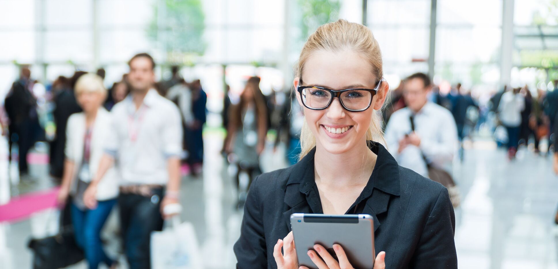 Frau mit Tablet in der Hand auf einer Messe