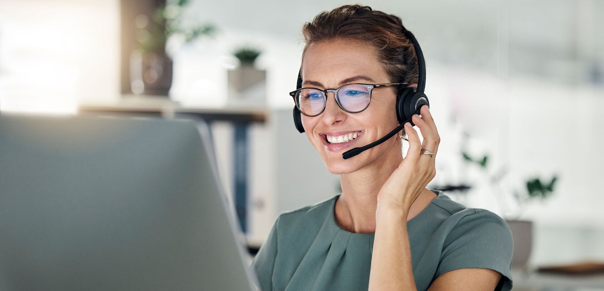 Kundenbetreuerin mit Headset im Kundengespräch am Computer.